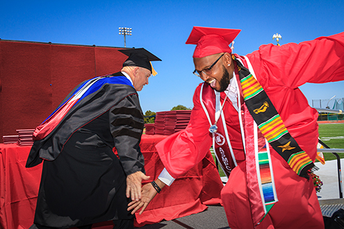 College president slaps hands with a MPC graduate on stage.