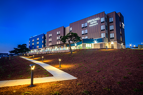 Exterior view of the western facing side of a Marriott Hotel with deep blue twilight sky in the background and a lit path winding up to it.