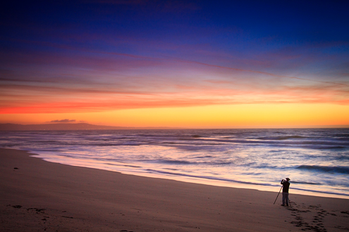 Lone photographer at the beach photographing the sunset