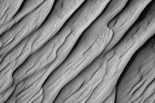 Wind and rain give texture to a coastal sand dune. Part of a black and white portfolio of landscape and abstract nature photographs depicting Science Fiction-like imagery from distant galaxies to Earth’s prehistoric natural history. 
