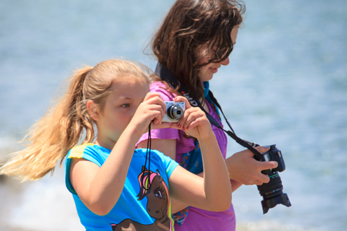 Two young students photographing at the beach.
