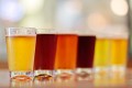 Showing a spectrum of color, pint glasses of craft beer line the bar.
