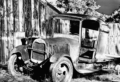 Dilapidated truck next to a wooden barn