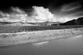 Storm clouds, mountains, tilled field, and reservoir.
