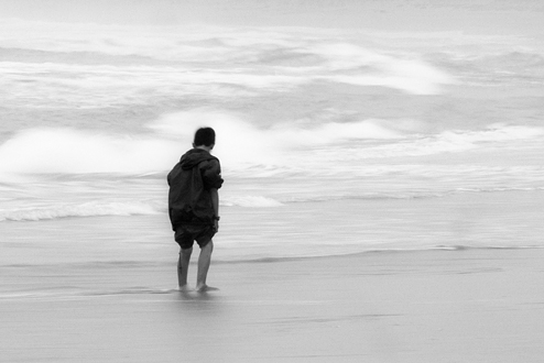 I shot this during a CSU Monterey Bay Photo Club field trip to Moss Landing. We all showed up looking for a pretty sunset. Yet, it was the fisherman on the jetty, a flock of seagulls, and some kids playing on the beach that fascinated me. This little boy wandered the edge of the cold winter surf. Perhaps deep in thought, maybe just mesmerized by the water being swept over his feet back to a wintery gray Pacific. 