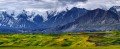 Green tundra leading to dark colored mountains and dramatic clouds.