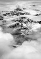 Snow-covered mountain peaks rise up through thick clouds.