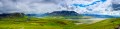 Panoramic photo os expansive landcsape of tundra glacial rivers, mountains, and storm clouds.