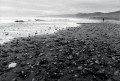 Rocky shoreline with a solitary figure far down the beach.