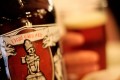 Close up of Dead Guy Ale bottle with out of focus hand holding a pint of beer.
