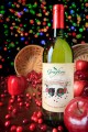 Wine Bottle surrounded by spilt apples and cranberries with colorful background lights.