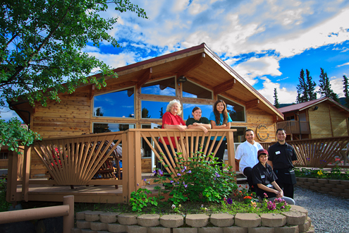 The staff of the Denali River Cabins pose in front of their Roadhouse restaurant on a sunny summer day. 