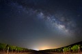 The Milky Way spans the night sky above vineyards with the distant lights from Highway 101.