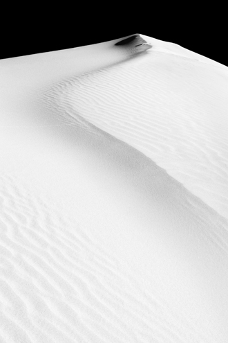 The deep blue sky goes to black with a deep red filter over the gently curving crest of a pure white sand dune. Part of a black and white portfolio of landscape and abstract nature photographs depicting Science Fiction-like imagery from distant galaxies to Earth’s prehistoric natural history. This photograph was recognized by the International B&W Spider Awards. 