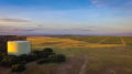 Ranch land at sunset with oak trees, strawberry fields and water tank.
