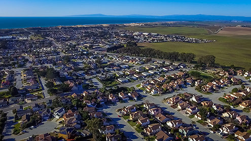 Aerial photo of Marina residential neighborhood with Armstrong Ranch, and the Monterey Bay and Santa Cruz in the background from a drone. 