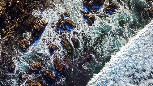 Looking down at the surf washing in and out over rocks and a kelp forest at the tip of the Monterey Peninsula. FAA certified sUAS/Drone photography. 