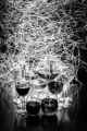 A collection of wine glasses with a crazy amount of light streaks behind them in black & white.