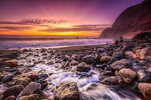 Limekiln Creek rushes across a rocky beach to the sea while campers enjoy the sunset. 