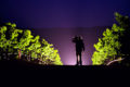Backlit silhouette of a farmer in a vineyard at night that looks like the Scheid Vineyards logo.